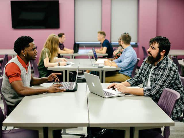 students working on laptops inside classroom